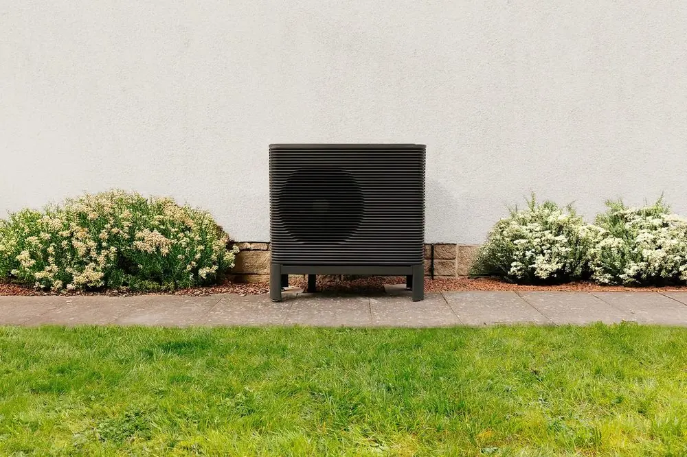 Warmtepomp-buitenunit tegen een tuinmuur